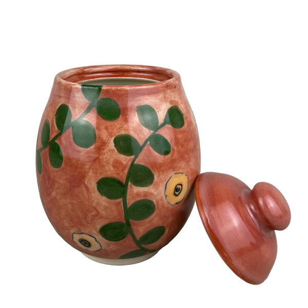 Ceramic jar with green leaf patterns on a gray background