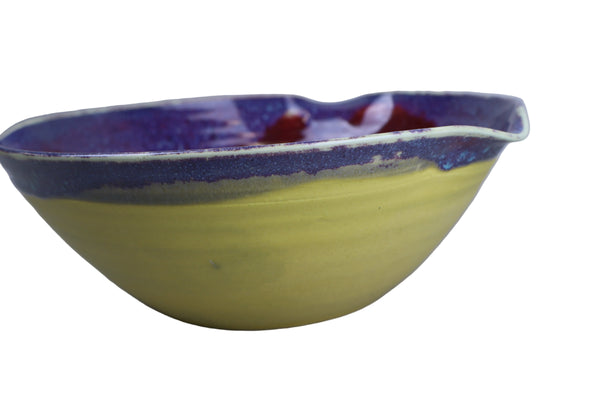 Yellow ceramic bowl with a blue rim on a gray background