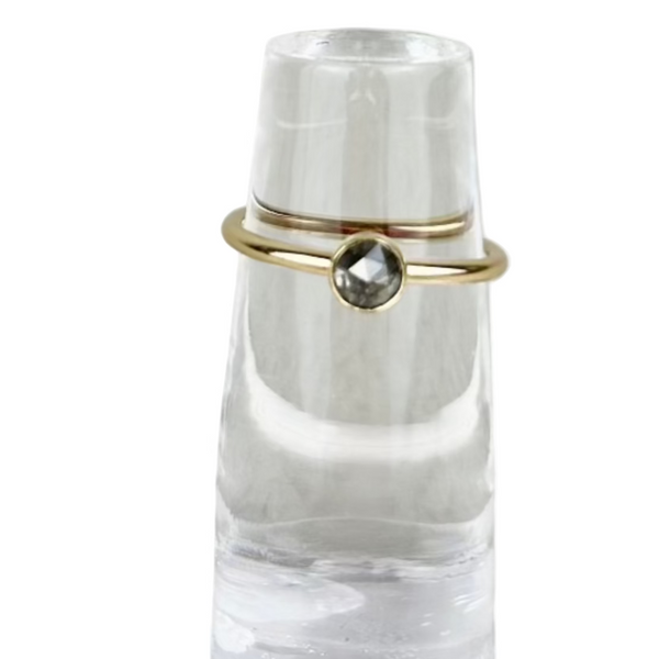 Clear crystal ring holder with two gold rings on a light gray surface