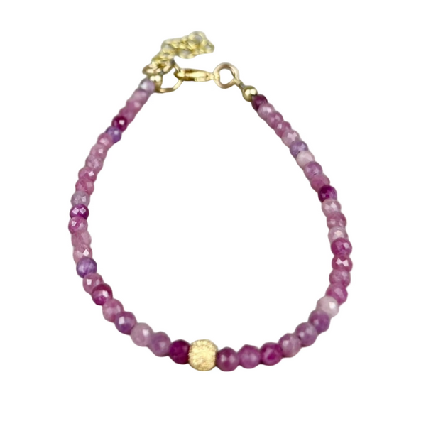 Beaded bracelet with pink and gold accents on a gray background