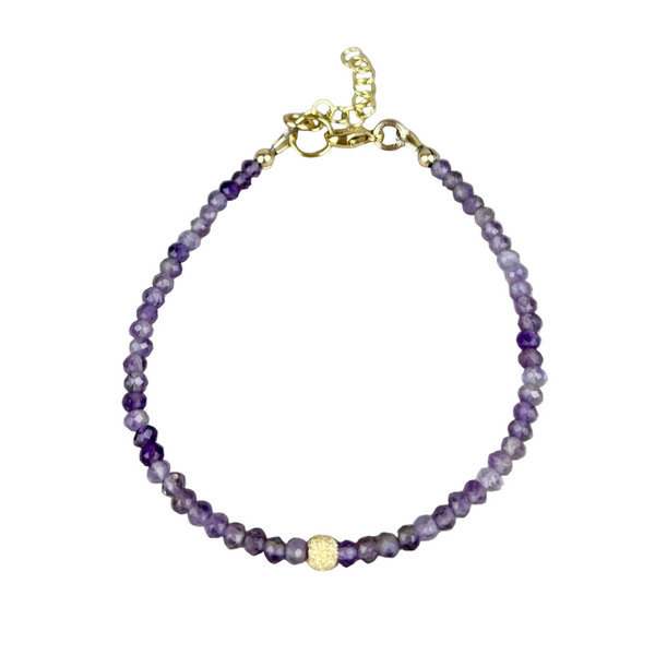 Purple beaded bracelet with gold clasp on a gray background