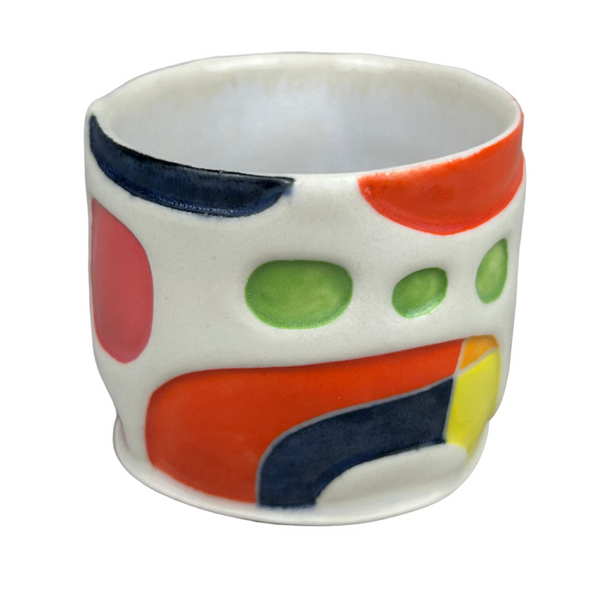 Small ceramic cup with colorful abstract design on a gray background