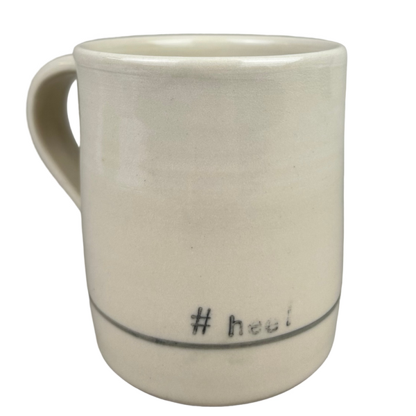 White ceramic mug with '# heel' text on a gray background