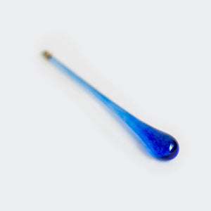 A long, slender blue glass rod or stick with a rounded teardrop-shaped end, photographed diagonally on a plain white background.