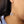 Close-up of a sterling silver threader earring with an engraved celestial face design, worn on a woman’s ear.