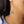 Close-up of a sterling silver threader earring with an engraved celestial face design, worn on a woman’s ear.