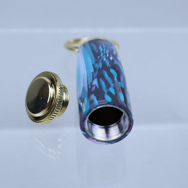 Two bottle caps, one gold and one with a blue and black pattern, on a clear background.