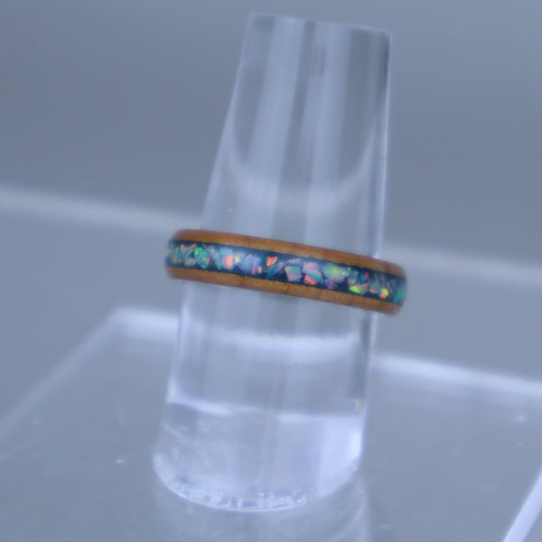 Ring with colorful gemstones on a clear stand against a gray background