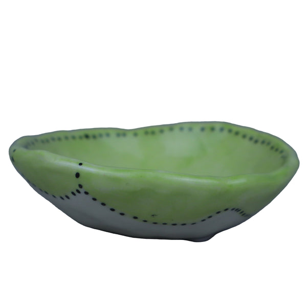 Green ceramic bowl with black dots on a gray background
