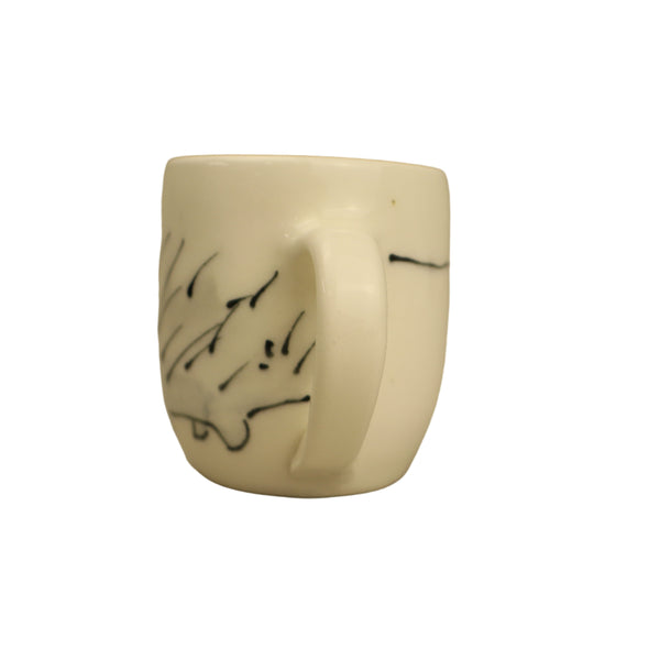 White ceramic mug with black abstract designs on a beige background