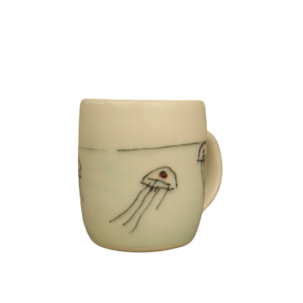 White ceramic mug with black and red jellyfish design on a beige background