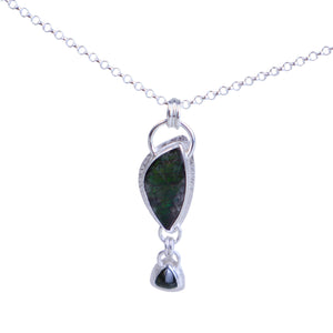 Silver necklace with a green pendant on a light gray background