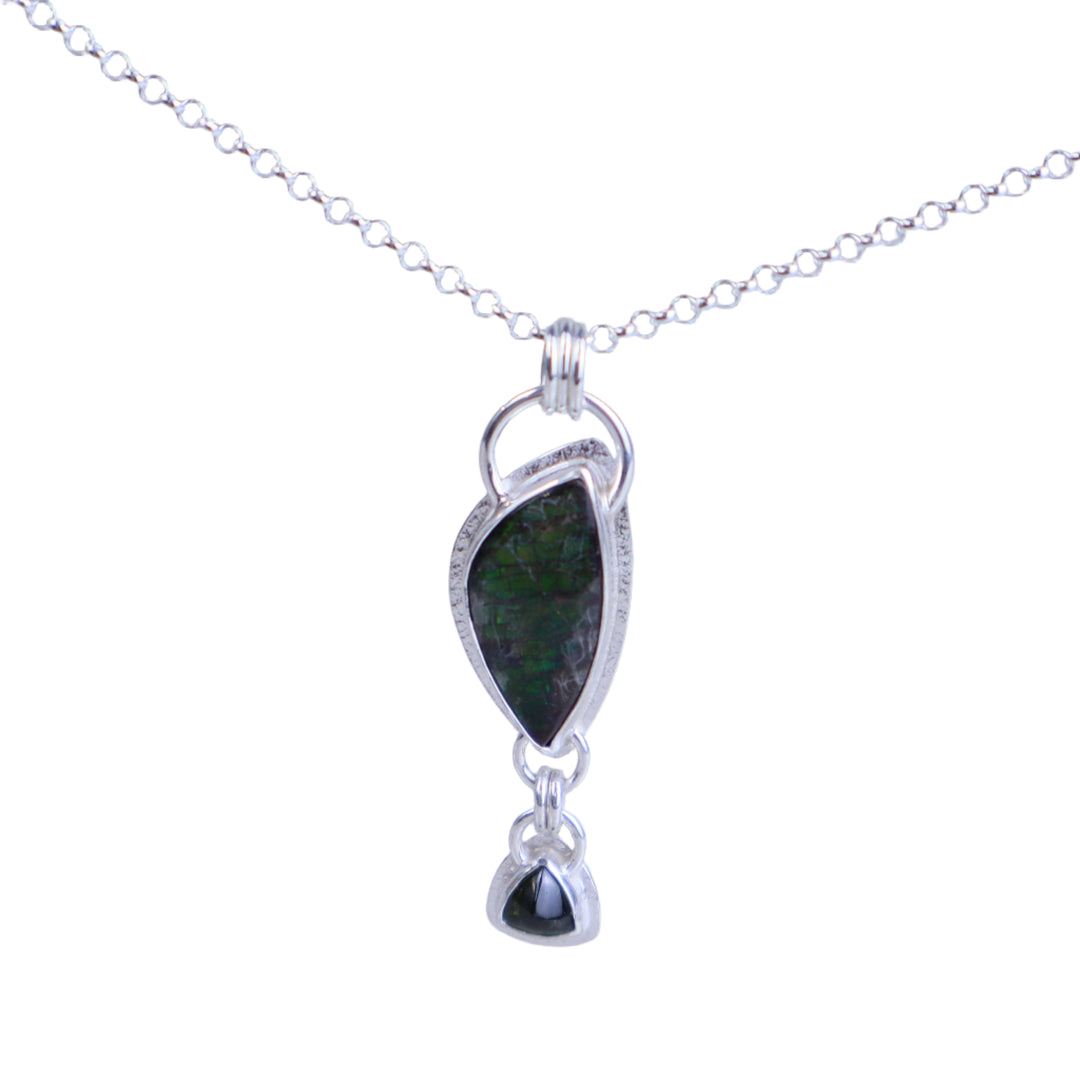 Silver necklace with a green pendant on a light gray background
