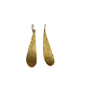 Pair of gold teardrop-shaped earrings on a beige background