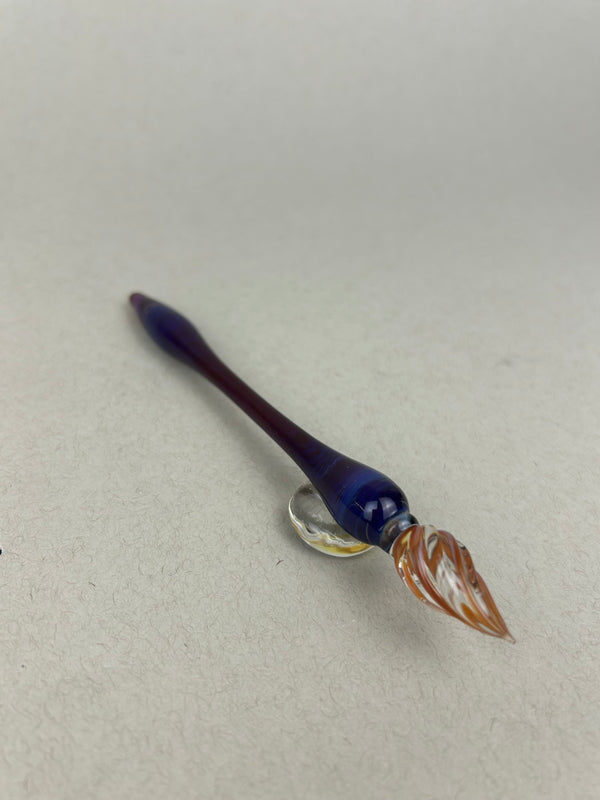 Handcrafted glass dip pen and tester pen set in swirling purple and gold tones, displayed together on a neutral background