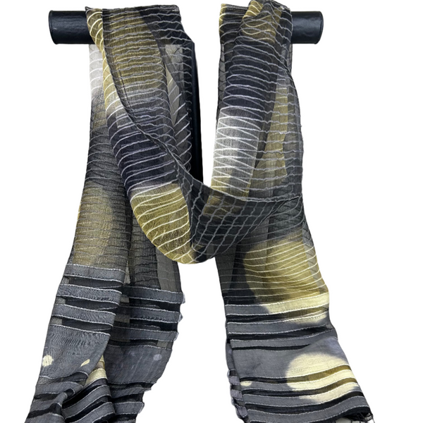 Striped scarf with black, gray, and yellow pattern on a stand against a white background