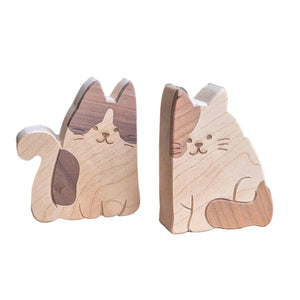 Two small wooden cat figurines made from natural wood, one standing and one sitting.