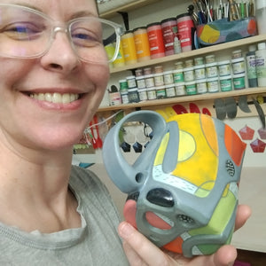 Person holding a colorful object with a paint set in the background