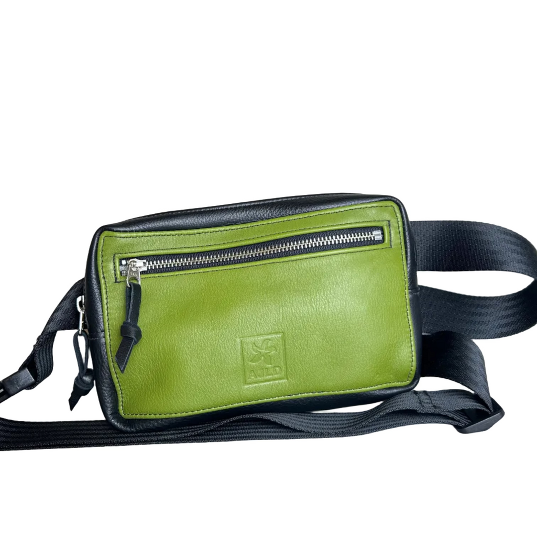 A green and black leather crossbody bag with a front zippered pocket and a black strap, shown on a neutral gray background.